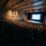 Audience seated in a large lecture hall watching an astrophysics presentation on a screen